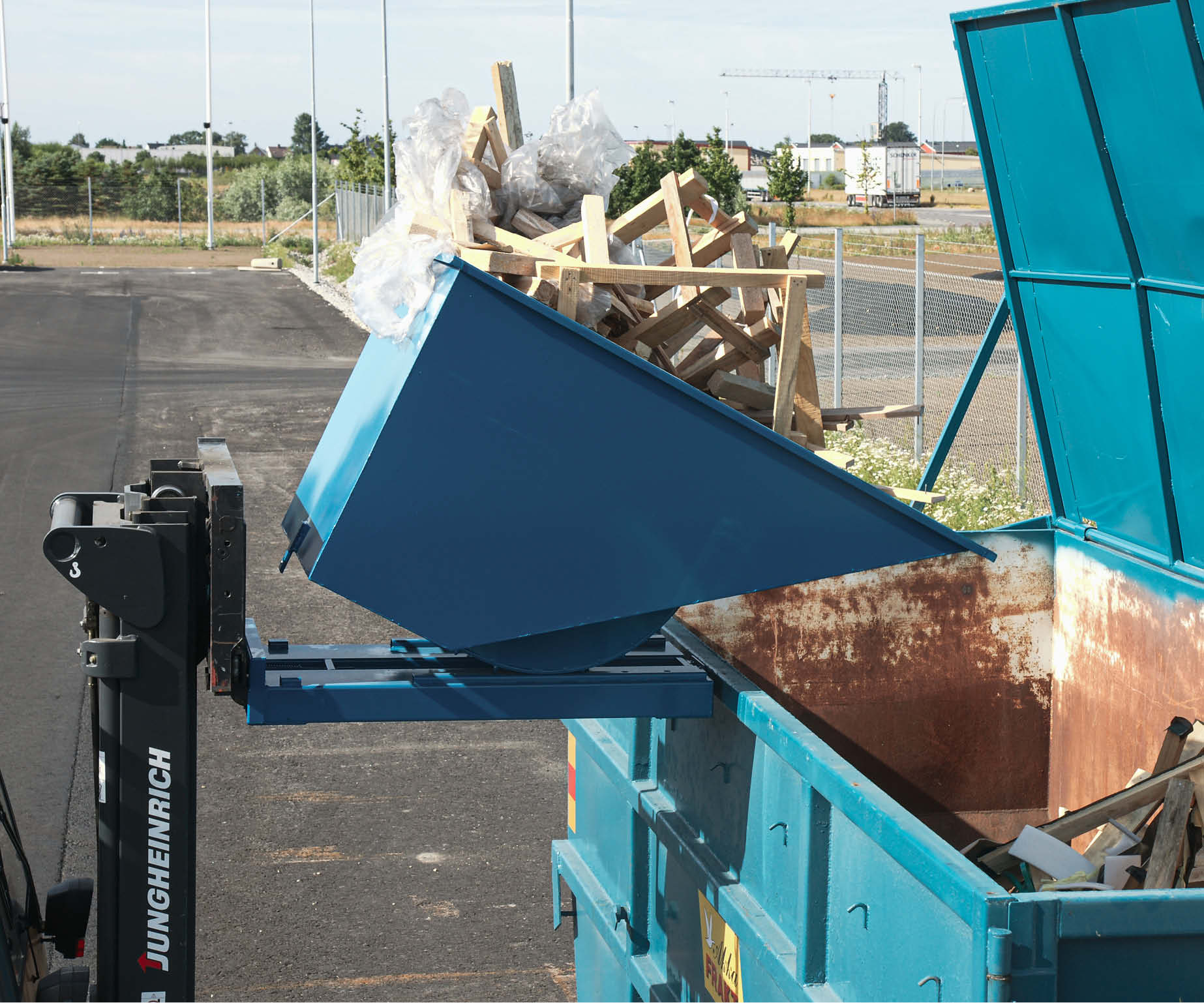 Tippcontainer fäst på truckgafflar som tippar skräp i en container
